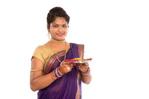 Retrato de una niña tradicional india sosteniendo pooja thali con foto diya, diwali o deepavali con manos femeninas sosteniendo una lámpara de aceite durante el festival de la luz sobre fondo blanco.