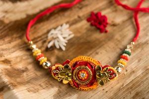 Indian festival Raksha Bandhan background with an elegant Rakhi, Rice Grains and Kumkum. A traditional Indian wrist band which is a symbol of love between Brothers and Sisters. photo