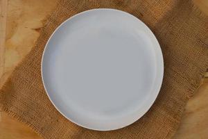 Empty white plate with rustic brown burlap cloth on rustic wooden table. Top view images or flatlay images photo