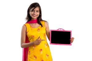 Beautiful young girl holding and showing something on a chalkboard or slate, isolated over white background photo