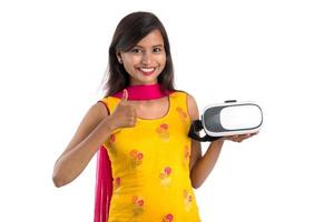niña tradicional india sosteniendo y mostrando dispositivo vr, caja vr, gafas, casco de gafas de realidad virtual 3d, chica con tecnología de imagen moderna del futuro sobre fondo blanco.