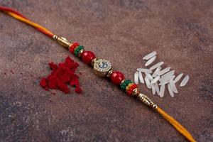 Raksha Bandhan Rakhi with rice grains and kumkum on stone background, Traditional Indian wrist band which is a symbol of love between Brothers and Sisters. photo