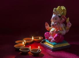 Clay diya lamps lit with Lord Ganesha during Diwali Celebration. Greetings Card Design Indian Hindu Light Festival called Diwali photo