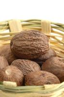 Nutmeg in bamboo basket isolated on white background photo