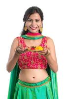 Beautiful Indian young girl holding pooja thali or performing worship on a white background photo