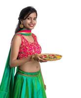 Portrait of a Indian Traditional Girl holding Diya, Girl Celebrating Diwali or Deepavali with holding oil lamp during festival of light on white background photo