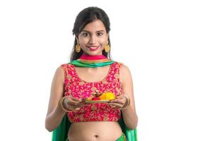 Beautiful Indian young girl holding pooja thali or performing worship on a white background photo