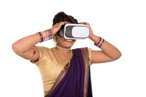 India tradicional joven en sari mirando a través del dispositivo vr foto