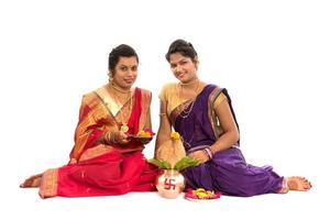 Hermanas tradicionales indias que realizan adoración, festival indio, kalash de cobre con hojas de coco y mango con decoración floral, esencial en la puja hindú. foto
