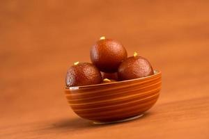 Gulab Jamun in bowl on wooden background. Indian Dessert or Sweet Dish. photo