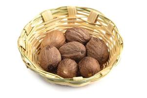 Nutmeg in bamboo basket isolated on white background photo