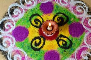 Clay diya lamps lit during diwali celebration, Rangoli in background photo