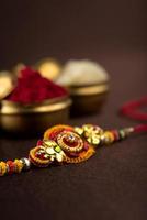 Fondo de raksha bandhan con un elegante rakhi, granos de arroz y kumkum. una pulsera tradicional india que es un símbolo del amor entre hermanos y hermanas. foto