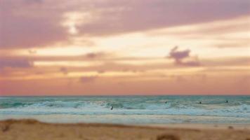 Cinemagraph de grupo de surfistas surfeando en el mar Mediterráneo al atardecer en la playa de Palmahim en Israel video