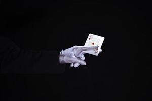 magician holding aces playing card fingers against black background photo