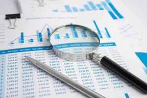 Magnifying glass on charts graphs paper. Financial development, Banking Account, Statistics, Investment Analytic research data economy, Stock exchange trading, Business office company meeting concept. photo