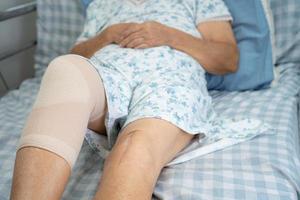 Asian senior or elderly old lady woman patient with knee support pain joint on bed in nursing hospital ward, healthy strong medical concept. photo