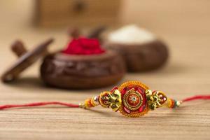 Indian festival Raksha Bandhan background with an elegant Rakhi, Rice Grains and Kumkum. A traditional Indian wrist band which is a symbol of love between Brothers and Sisters. photo