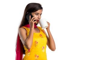 Pretty young girl calling on smartphone device while drinking tasty coffee or tea beverage photo