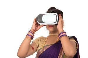 India tradicional joven en sari mirando a través del dispositivo vr foto