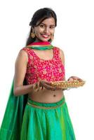 Portrait of a Indian Traditional Girl holding Diya, Girl Celebrating Diwali or Deepavali with holding oil lamp during festival of light on white background photo