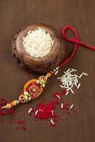 Indian festival Raksha Bandhan background with an elegant Rakhi, Rice Grains and Kumkum. A traditional Indian wrist band which is a symbol of love between Brothers and Sisters. photo