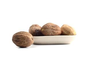 Nutmeg in white plate isolated on white background photo