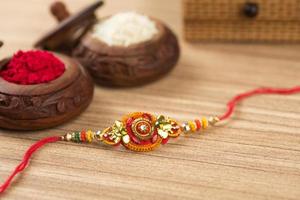 Indian festival Raksha Bandhan background with an elegant Rakhi, Rice Grains and Kumkum. A traditional Indian wrist band which is a symbol of love between Brothers and Sisters. photo