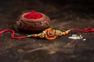 Raksha Bandhan background with an elegant Rakhi, Rice Grains and Kumkum. A traditional Indian wrist band which is a symbol of love between Brothers and Sisters. photo