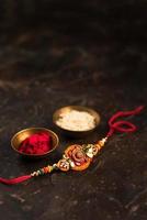 Raksha Bandhan background with an elegant Rakhi, Rice Grains and Kumkum. A traditional Indian wrist band which is a symbol of love between Brothers and Sisters. photo