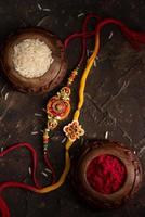 Raksha Bandhan background with an elegant Rakhi, Rice Grains and Kumkum. A traditional Indian wrist band which is a symbol of love between Brothers and Sisters. photo