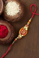 Indian festival Raksha Bandhan background with an elegant Rakhi, Rice Grains and Kumkum. A traditional Indian wrist band which is a symbol of love between Brothers and Sisters. photo