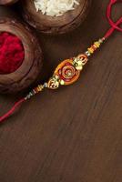 Indian festival Raksha Bandhan background with an elegant Rakhi, Rice Grains and Kumkum. A traditional Indian wrist band which is a symbol of love between Brothers and Sisters. photo