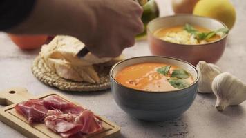 Serving salmorejo and egg in a bowl, with various ingredients around. Salmorejo is a tomato soup video