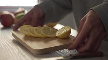Cutting lemon fruit into slices on a wood cutting board with a knife