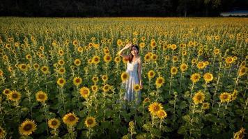 Happy joyful asian girl with sunflower enjoying nature and smile on summer in sunflower field. photo