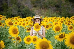 Happy joyful asian girl with sunflower enjoying nature and smile on summer in sunflower field. photo