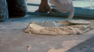 travailleur mettant de la gomme de ciment et de l'adhésif pour carreaux sur le sol avant de poser des carreaux de céramique video