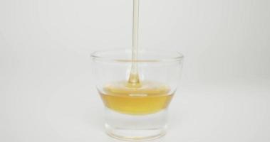 Close up, Pour the honey into a small glass. The honey flows slowly into the glass. On the white background. video