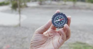 vooraanzicht, zwart kompas draait rond in een transparante hand. geeft de richting aan die naar buiten wijst. video
