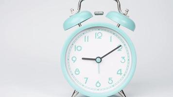 The blue alarm clock shows the running of time. The movement of the hands of the clock passed quickly. On the white background. video