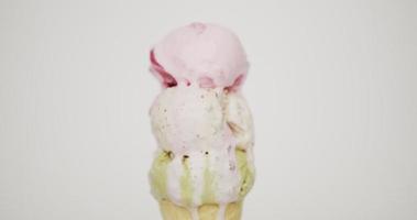 vista frontale, fusione di tre palline di gelato sul cono. dai coni sgorgano diversi gusti di gelato. sullo sfondo verde. video
