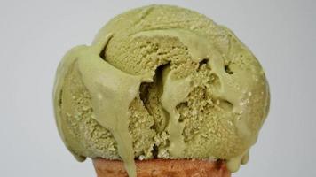 Melting of green tea ice cream on a cone. It flows slowly after the ice cream has melted. On the white background. video