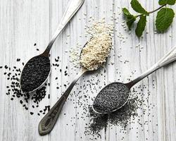 Black and white sesame seeds and poppy seeds in a spoons