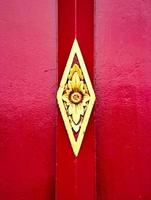 Antique red wood door with gold ancient Thai architectural art. photo