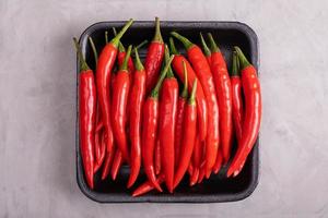 Whole red hot chili peppers in black tray photo