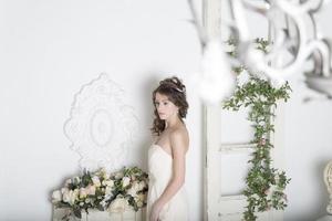 Girl in a white dress with flowers in the house. photo