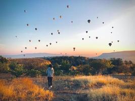 Back view caucasian woman solo traveler walk and watch balloons show in Cappadocia on travel adventure