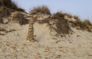 Photograph of a golden dune landscape with a pile of stones photo