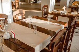 Glasses, flower fork, knife served for dinner in restaurant with cozy interior photo